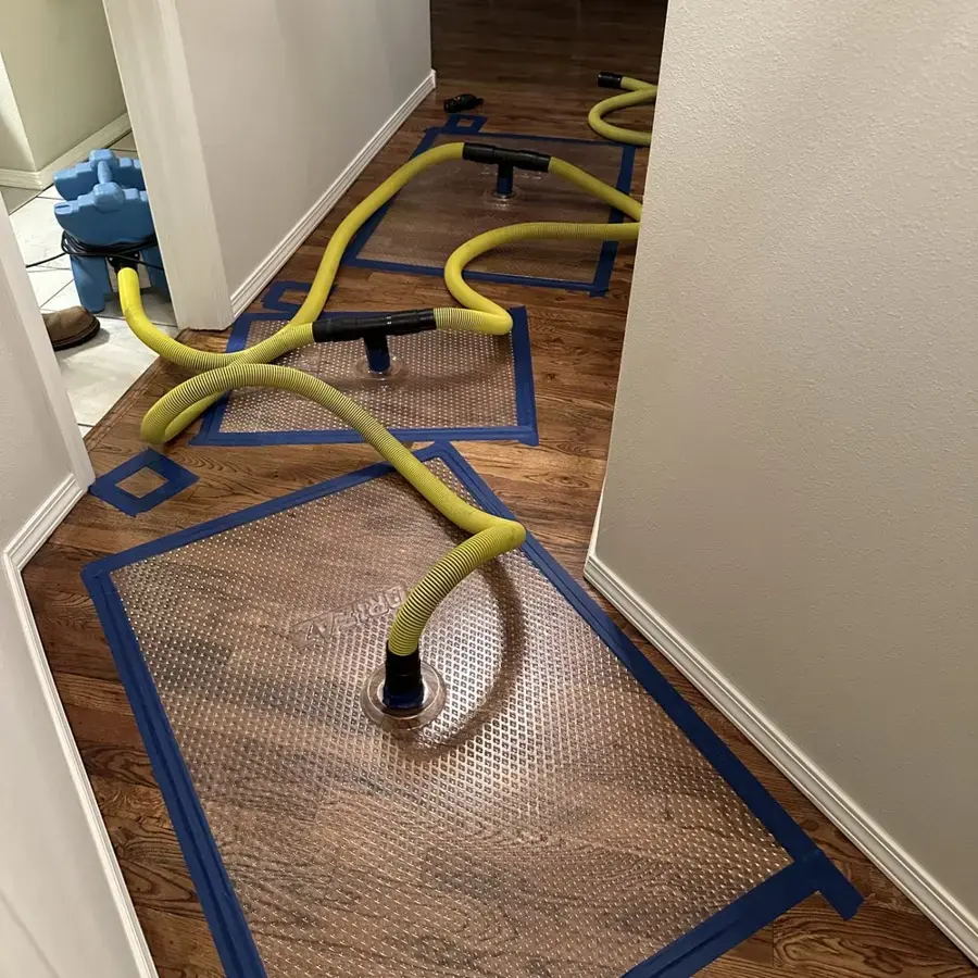 Floor drying mats and yellow hoses pulling water out of a hardwood hallway, hardwood drying in Owasso