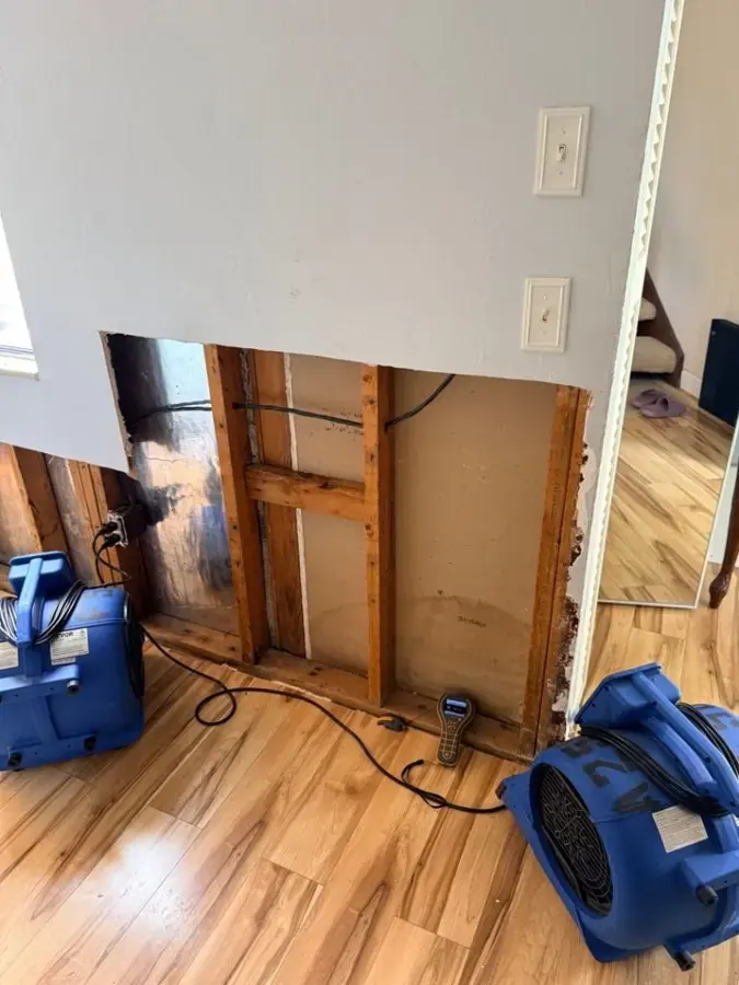 A lower wall cavity opened with air movers aimed at the framing, structural drying for an Owasso home