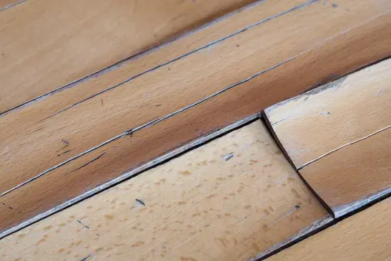 Hardwood floorboards cupped by water underneath, the kind of floor damage an Owasso leak causes