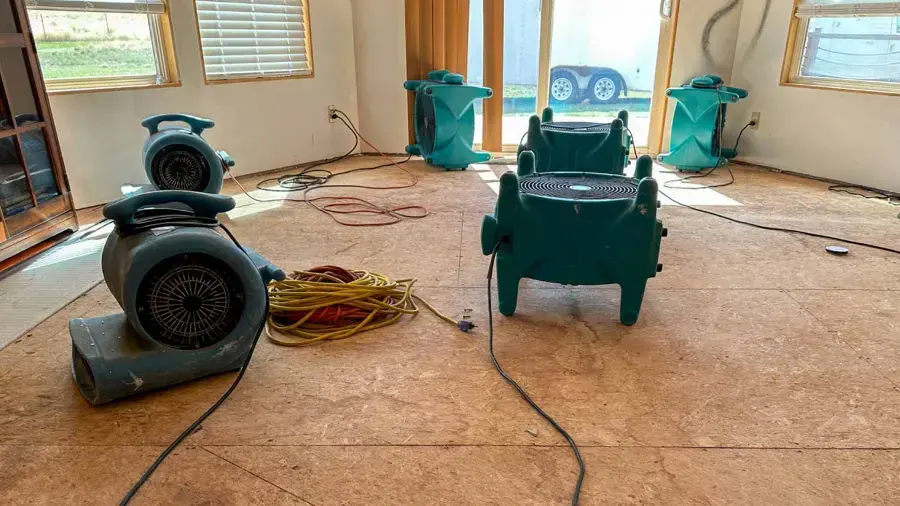 Air movers and a dehumidifier drying a room with the flooring pulled up, a water damage dry-out for an Owasso home