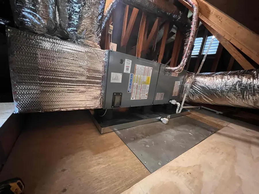 An attic air handler with its drain pan and insulated ducts, where attic AC condensate leaks start in Owasso homes