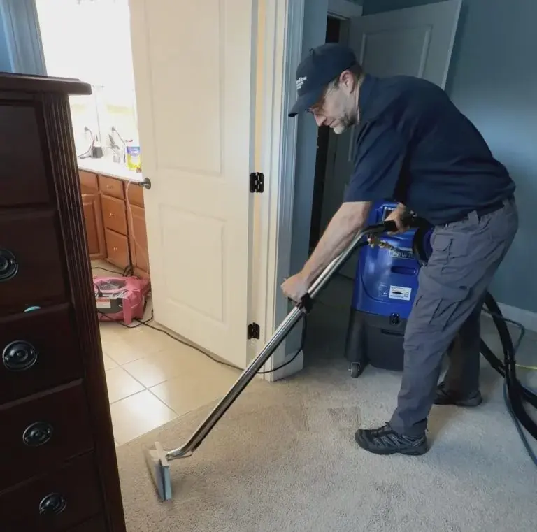 A technician pulling water out of wet hallway carpet with a portable extractor, the first step of water extraction for Owasso homes